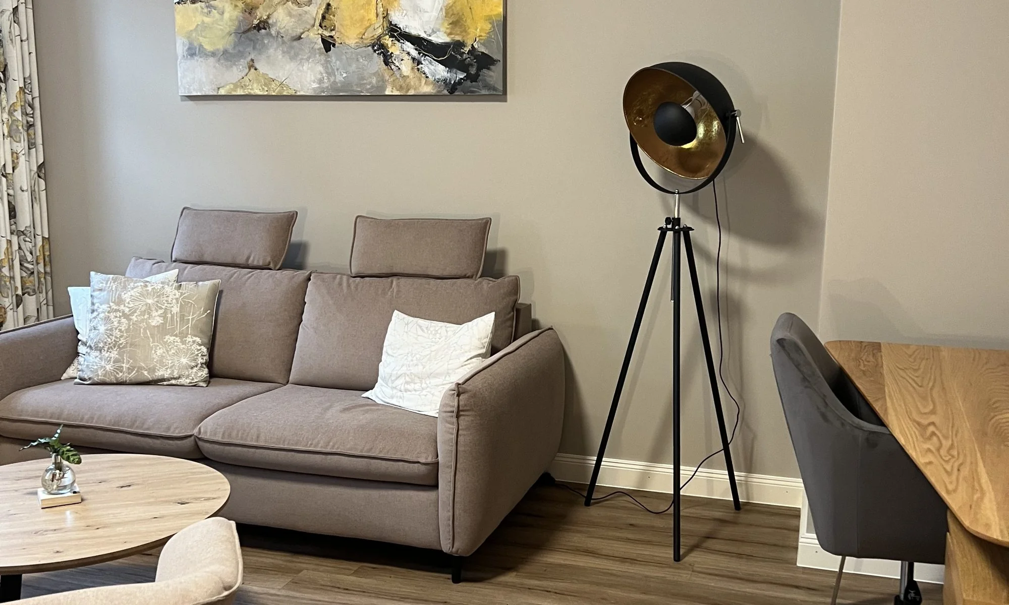 Helles Wohnzimmer mit Sofa, Holzmöbeln und hohen Altbaudecken